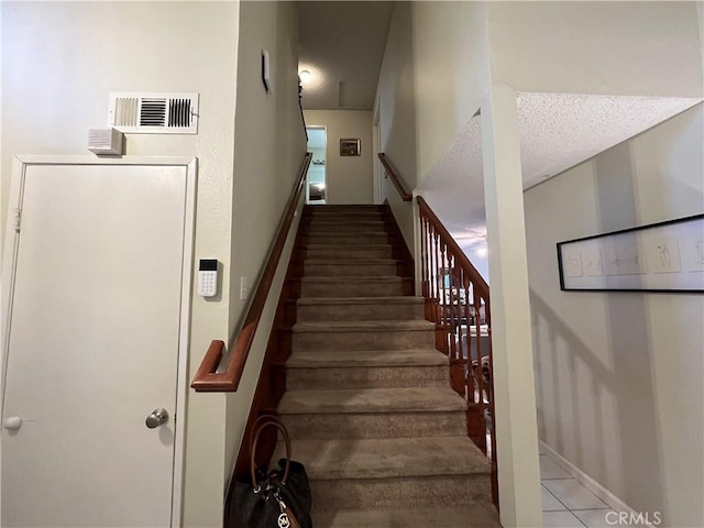 stairway with baseboards, visible vents, and a textured ceiling