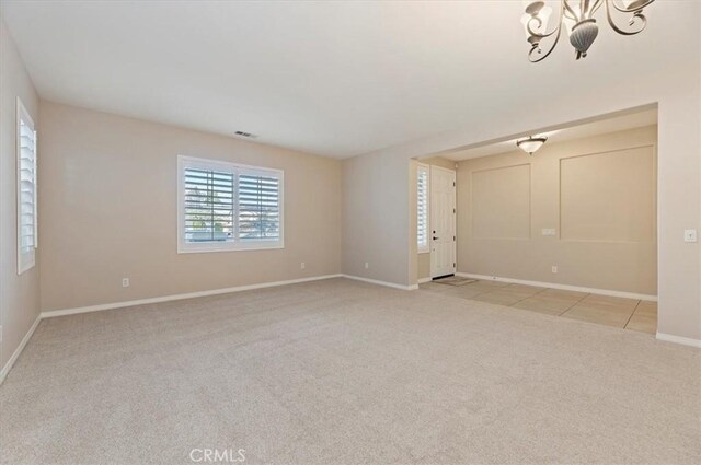 unfurnished room with light tile patterned floors, light colored carpet, visible vents, baseboards, and an inviting chandelier