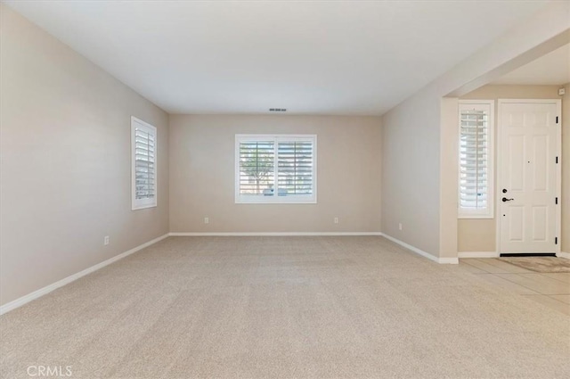 unfurnished room featuring light carpet, visible vents, and baseboards