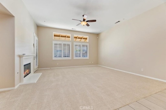 unfurnished living room with visible vents, baseboards, a ceiling fan, carpet, and a glass covered fireplace