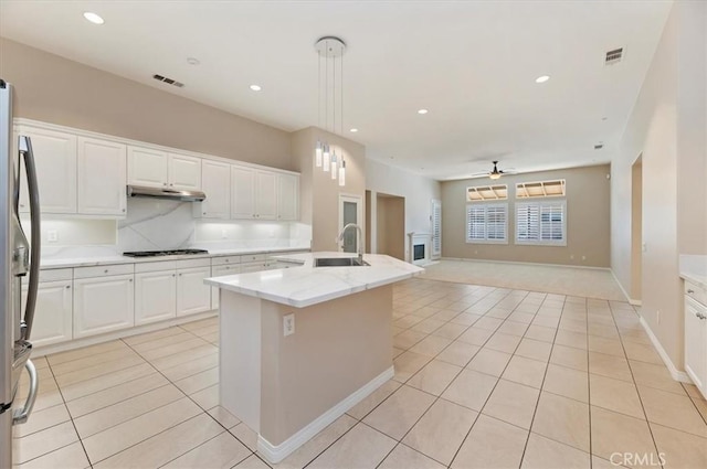 kitchen with pendant lighting, light tile patterned floors, open floor plan, white cabinets, and stainless steel fridge