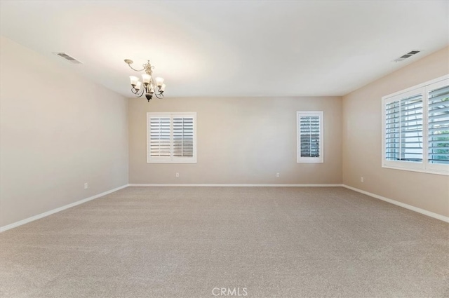 unfurnished room with a chandelier, light colored carpet, visible vents, and baseboards