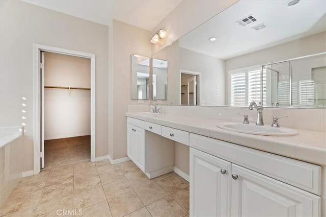 bathroom featuring a spacious closet, double vanity, a sink, and visible vents