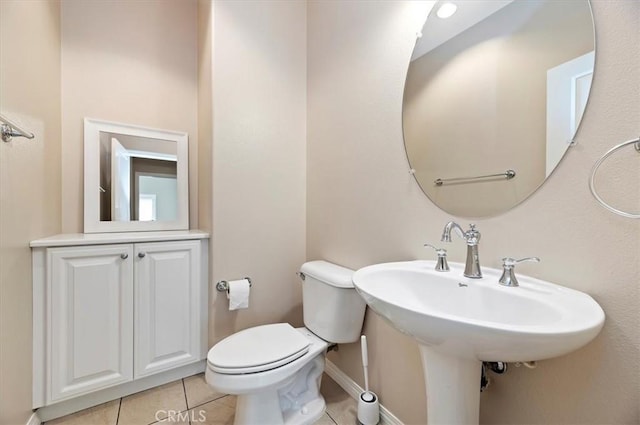 half bath featuring baseboards, toilet, and tile patterned floors