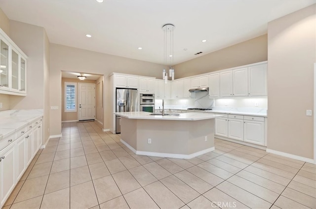 kitchen featuring light tile patterned floors, white cabinets, appliances with stainless steel finishes, under cabinet range hood, and a sink