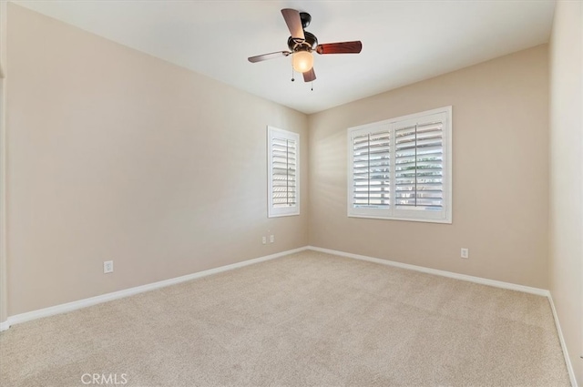 carpeted spare room with baseboards and a ceiling fan