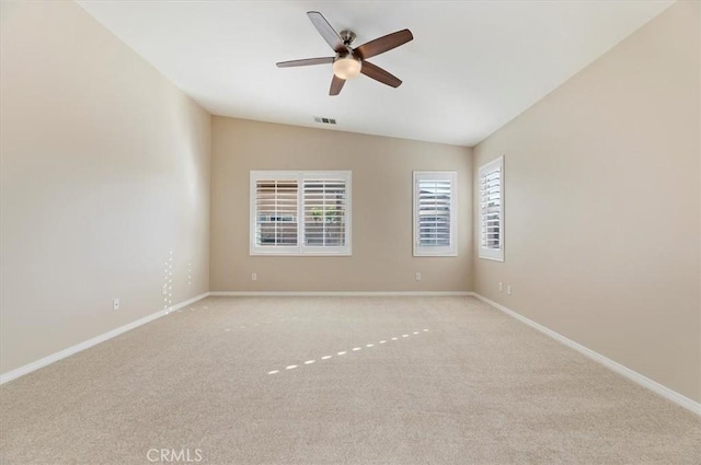 unfurnished room with carpet, visible vents, vaulted ceiling, and baseboards