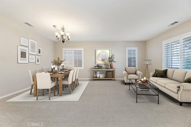 carpeted dining room featuring visible vents, baseboards, and an inviting chandelier