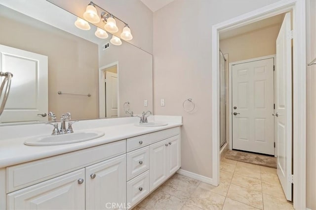 full bathroom with a shower stall, double vanity, a sink, and baseboards