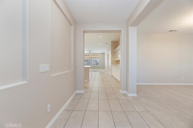 hall featuring visible vents, baseboards, and light colored carpet