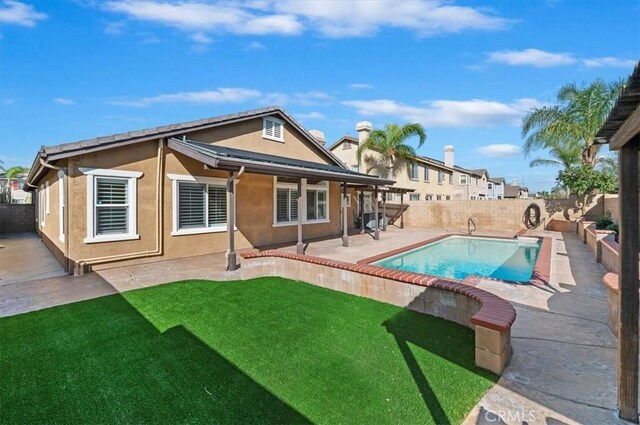 rear view of house with a patio, a fenced backyard, a lawn, a fenced in pool, and stucco siding