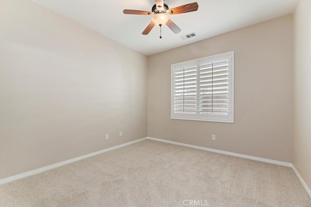 carpeted empty room with baseboards, visible vents, and a ceiling fan