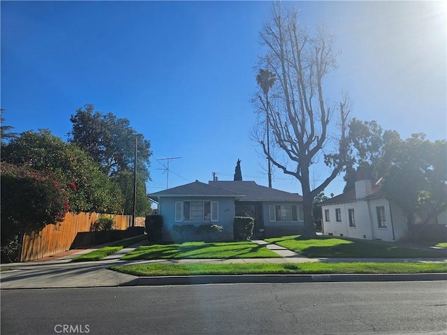 view of front facade with driveway, a front yard, and fence