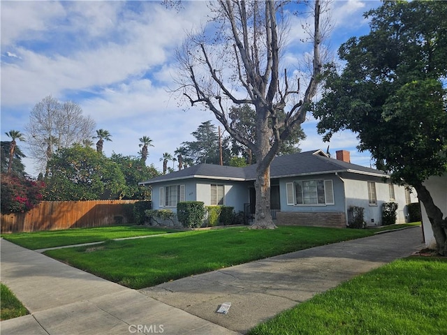 ranch-style house with stucco siding, a chimney, fence, and a front yard