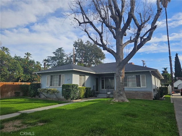 view of front of property featuring a front yard, fence, and stucco siding