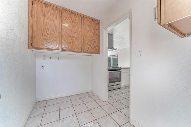 laundry room with cabinet space, light tile patterned floors, and baseboards