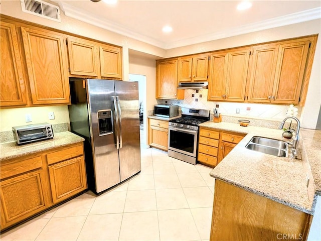 kitchen featuring under cabinet range hood, stainless steel appliances, a sink, visible vents, and ornamental molding