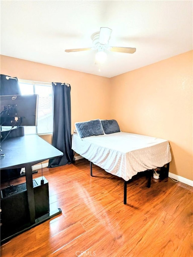 bedroom with ceiling fan, baseboards, and wood finished floors