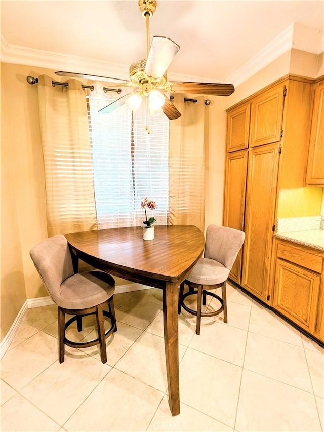 dining area with light tile patterned floors, ceiling fan, ornamental molding, and baseboards