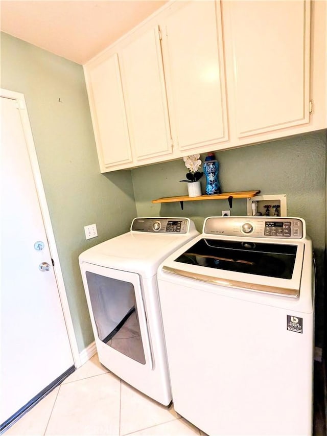 laundry area featuring cabinet space, light tile patterned floors, baseboards, and washing machine and clothes dryer