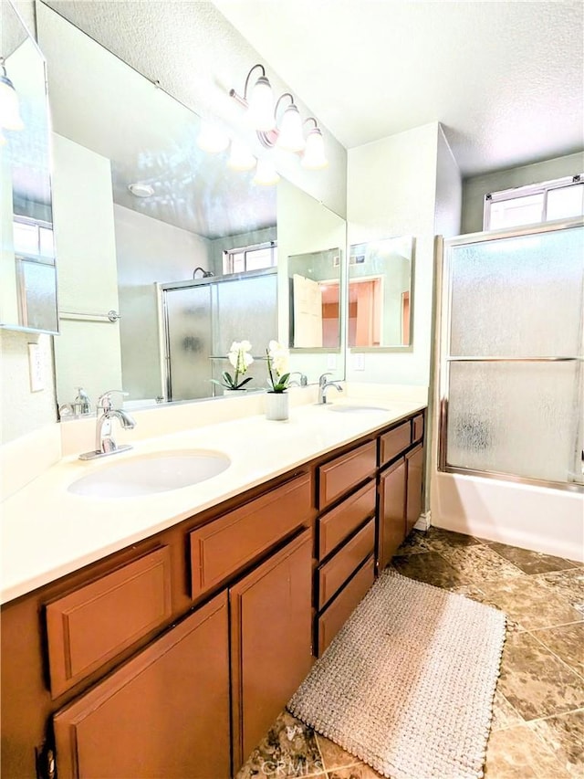 full bath with enclosed tub / shower combo, double vanity, a textured ceiling, and a sink