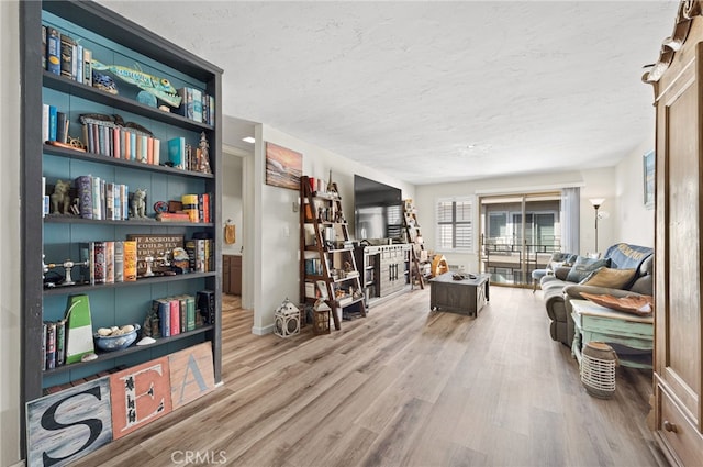 living area featuring a textured ceiling, baseboards, and wood finished floors