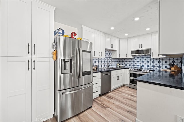 kitchen featuring stainless steel appliances, dark countertops, light wood-style floors, and tasteful backsplash