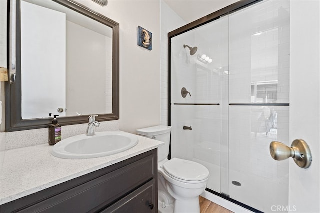 bathroom with wood finished floors, a stall shower, vanity, and toilet