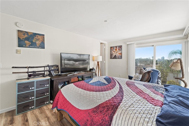 bedroom with access to outside, wood finished floors, and baseboards