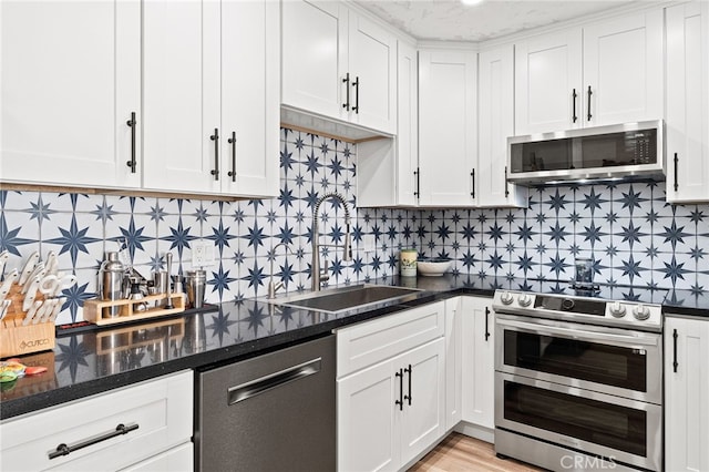 kitchen with appliances with stainless steel finishes, a sink, and white cabinetry