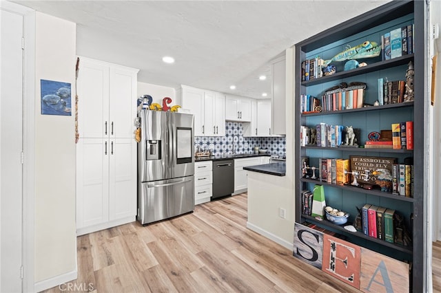 kitchen with dishwashing machine, stainless steel fridge, white cabinetry, and light wood finished floors