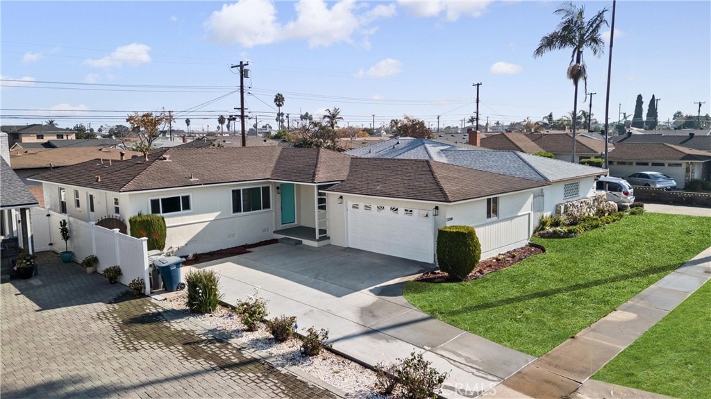 ranch-style house featuring concrete driveway, a residential view, an attached garage, fence, and a front yard