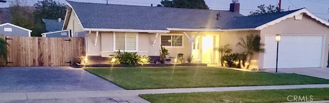 view of front facade featuring stucco siding, driveway, fence, a front yard, and a garage