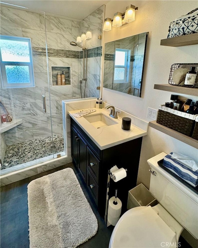 bathroom featuring a marble finish shower, toilet, and vanity