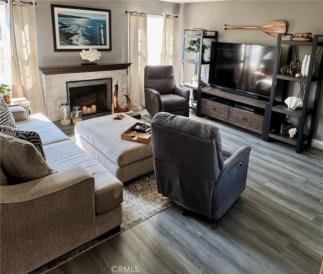 living area with a premium fireplace, a healthy amount of sunlight, and wood finished floors