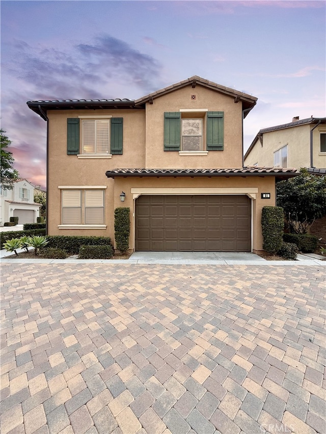 view of front of home with a tiled roof, a garage, and stucco siding