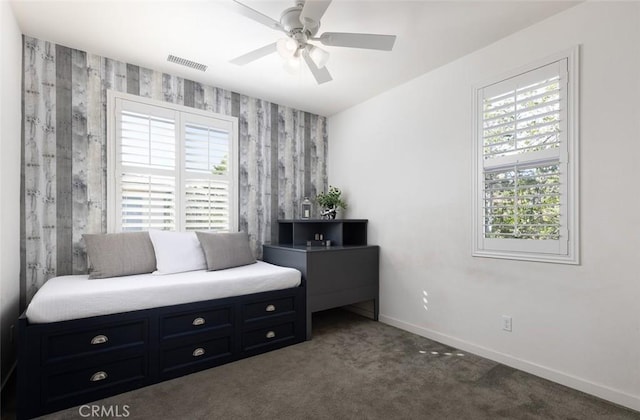 living area with visible vents, a ceiling fan, carpet floors, wallpapered walls, and baseboards