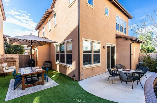 back of property featuring stucco siding, a fire pit, a patio, and fence