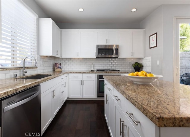 kitchen featuring tasteful backsplash, appliances with stainless steel finishes, light stone counters, and a sink