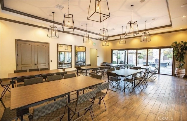 dining area featuring a towering ceiling, crown molding, a tray ceiling, and wood finished floors