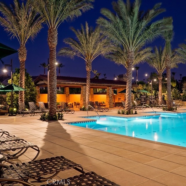 pool at twilight with a community pool and a patio area