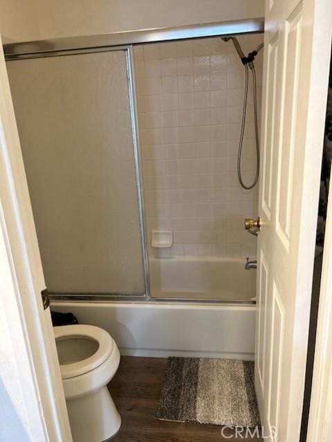 full bath featuring shower / bath combination with glass door, wood finished floors, and toilet