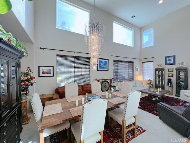 dining space featuring a towering ceiling, visible vents, and a notable chandelier