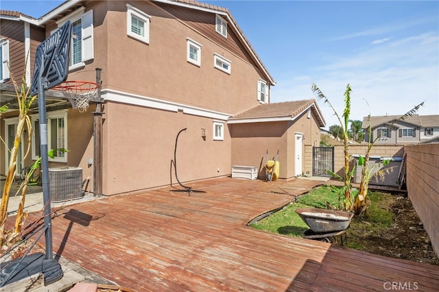 back of property featuring a deck, central air condition unit, fence, a gate, and stucco siding