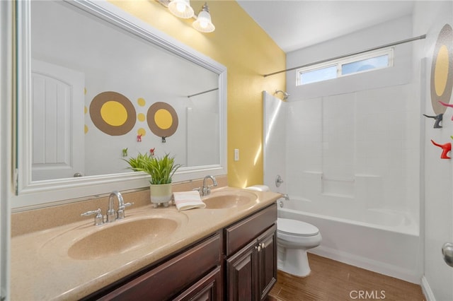 bathroom with double vanity, shower / washtub combination, a sink, and toilet