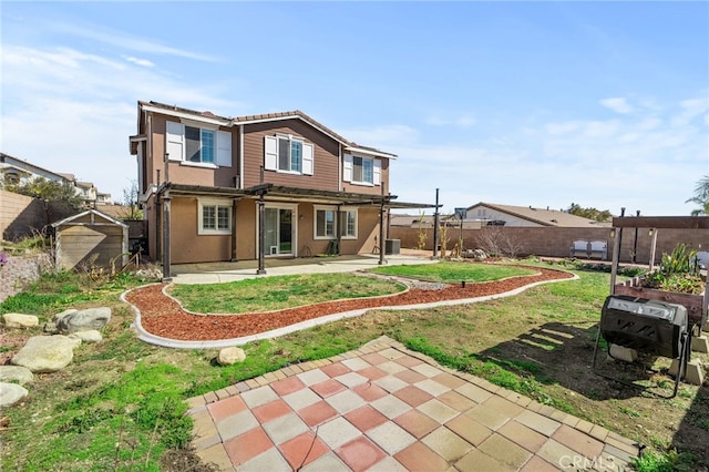 rear view of house with stucco siding, a fenced backyard, and a patio