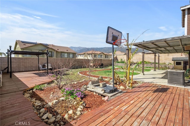 wooden terrace with a patio, central air condition unit, a mountain view, a pergola, and a fenced backyard