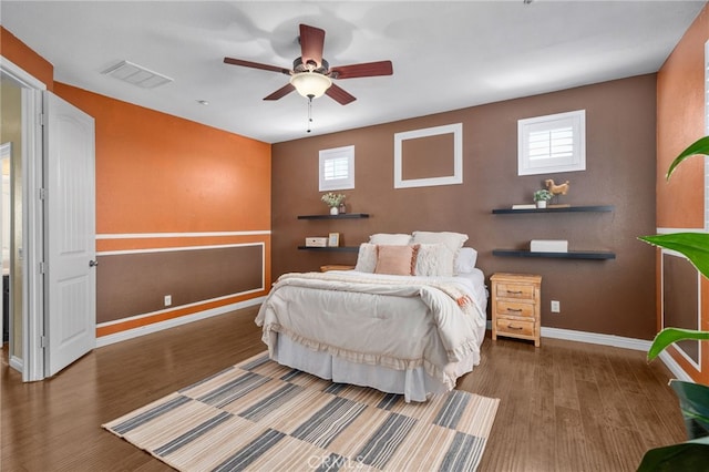 bedroom with multiple windows, wood finished floors, visible vents, and baseboards