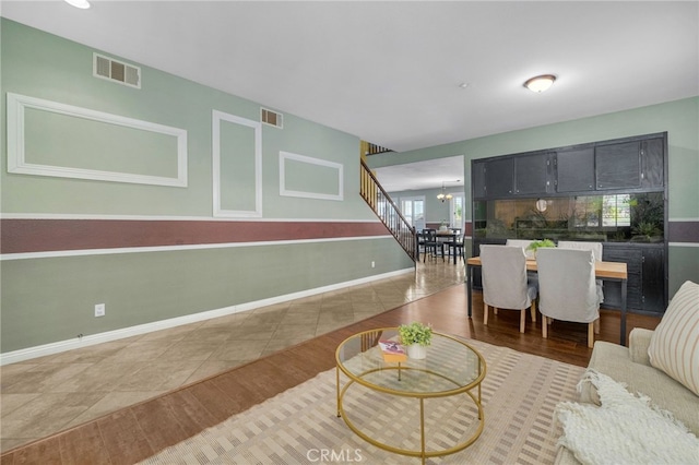 living room featuring stairs, wood finished floors, visible vents, and an inviting chandelier