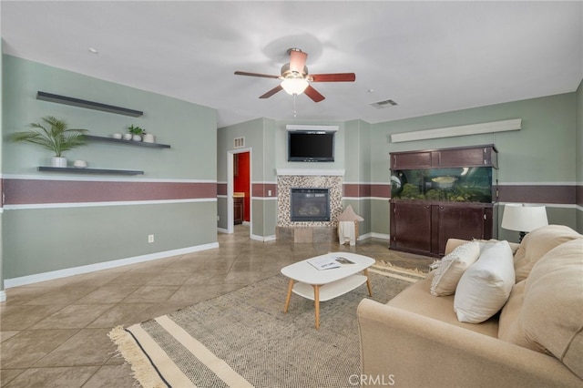 tiled living room featuring a tile fireplace, visible vents, ceiling fan, and baseboards